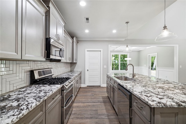 kitchen featuring stainless steel appliances, sink, tasteful backsplash, decorative light fixtures, and dark hardwood / wood-style flooring