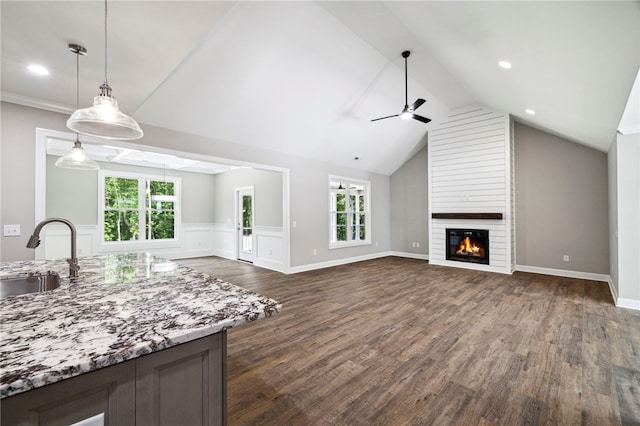 unfurnished living room featuring sink, ceiling fan, dark hardwood / wood-style floors, a fireplace, and lofted ceiling