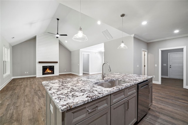 kitchen featuring light stone counters, vaulted ceiling, sink, dark hardwood / wood-style floors, and a large fireplace