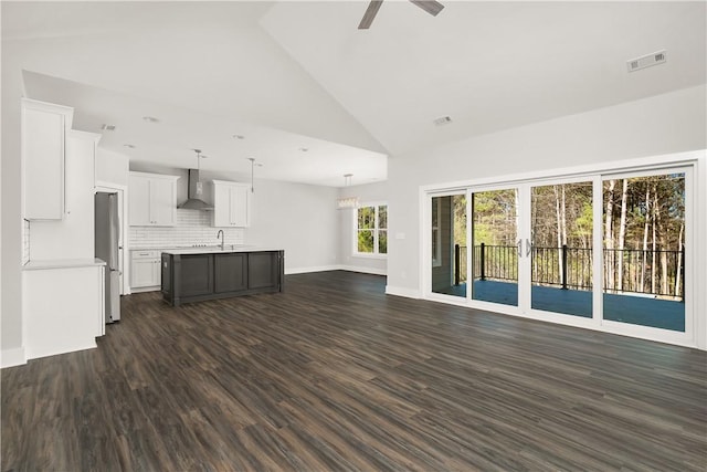 unfurnished living room with ceiling fan, sink, dark hardwood / wood-style floors, and high vaulted ceiling