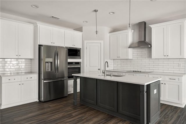 kitchen with wall chimney exhaust hood, sink, hanging light fixtures, appliances with stainless steel finishes, and white cabinets