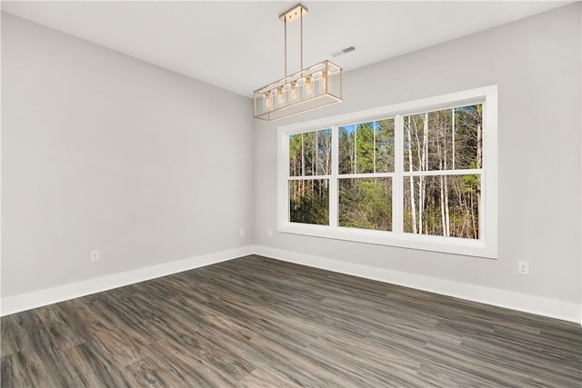 unfurnished dining area with dark hardwood / wood-style floors, a wealth of natural light, and a notable chandelier