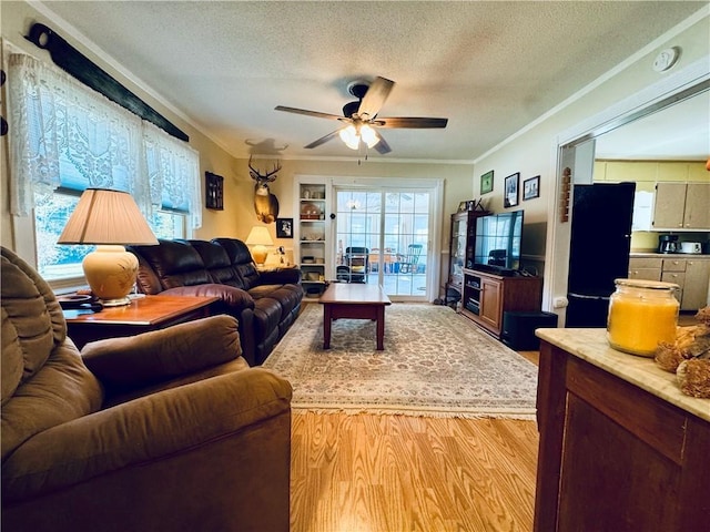 living room with crown molding, ceiling fan, light hardwood / wood-style floors, and a textured ceiling