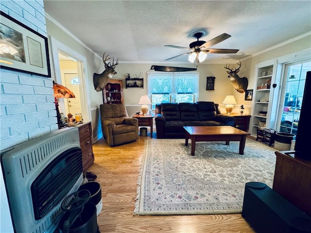 living room featuring heating unit, crown molding, a textured ceiling, a wood stove, and light wood-type flooring