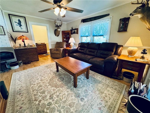 living room featuring heating unit, ornamental molding, ceiling fan, and light wood-type flooring