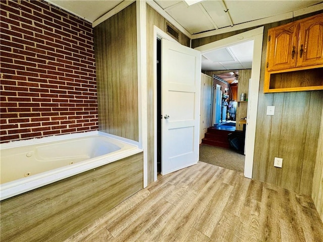 bathroom with a bath, hardwood / wood-style floors, and wood walls