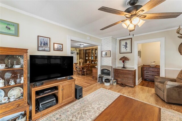 living area with ornamental molding, ceiling fan, and light wood-style flooring