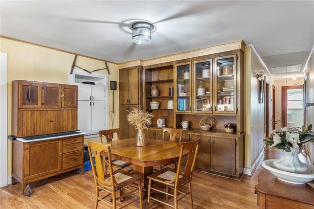 dining room with light wood finished floors, attic access, and baseboards