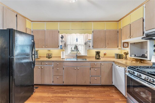 kitchen featuring light countertops, freestanding refrigerator, a sink, white dishwasher, and stainless steel gas range oven