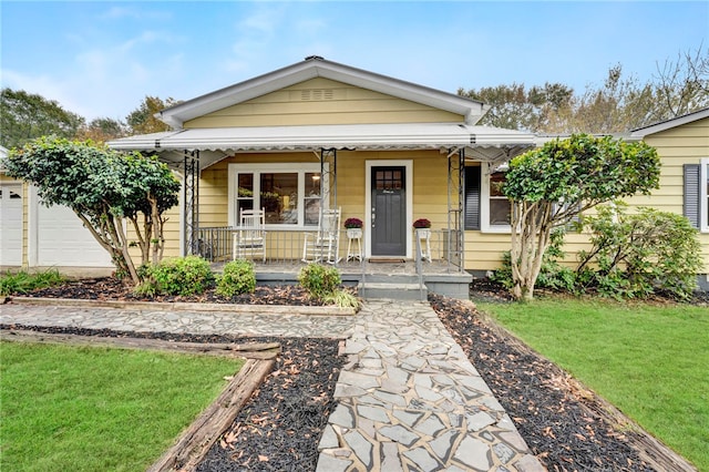 bungalow-style house with a garage, a front lawn, and covered porch