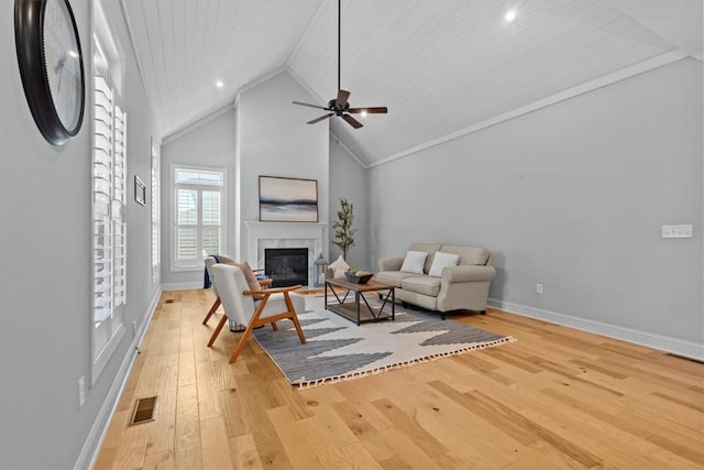 living room with ceiling fan, wooden ceiling, a premium fireplace, crown molding, and light wood-type flooring