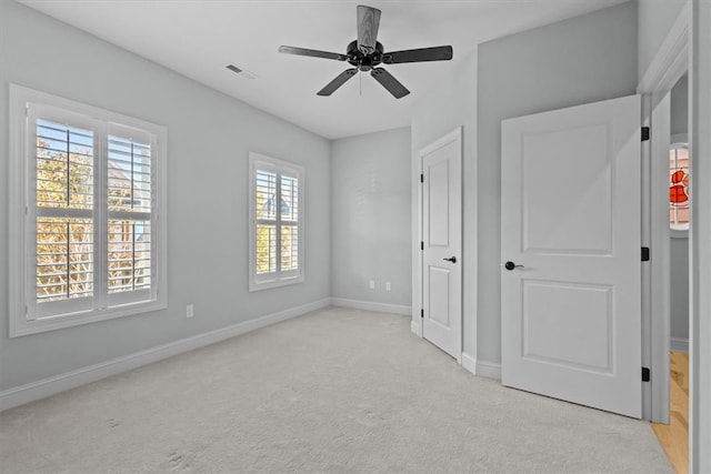 unfurnished bedroom featuring ceiling fan, light carpet, and multiple windows