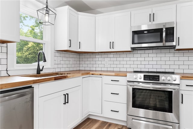 kitchen featuring stainless steel appliances, butcher block countertops, and white cabinetry