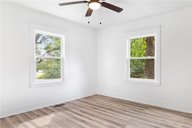 empty room with plenty of natural light, light hardwood / wood-style floors, and ceiling fan