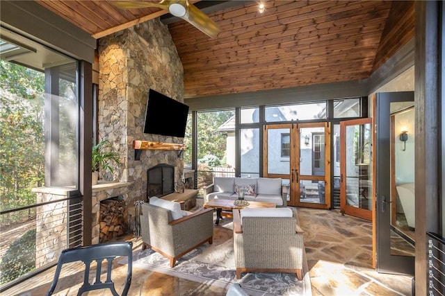 sunroom featuring french doors, vaulted ceiling, ceiling fan, wooden ceiling, and a stone fireplace