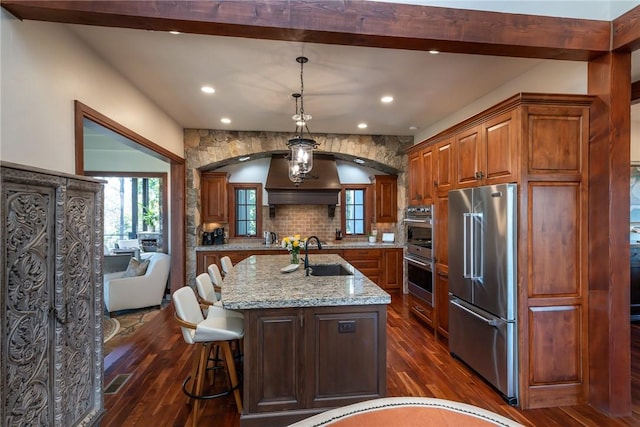 kitchen featuring sink, hanging light fixtures, an island with sink, dark hardwood / wood-style flooring, and stainless steel appliances