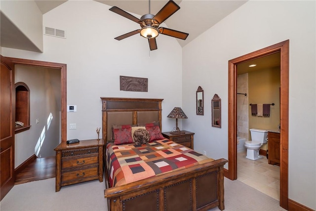 bedroom featuring light tile patterned floors, ensuite bath, ceiling fan, and lofted ceiling