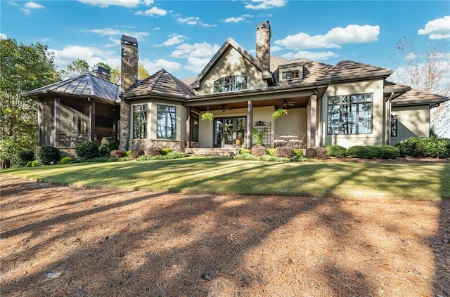 rear view of property with a sunroom, ceiling fan, and a yard