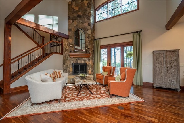 living room featuring a fireplace, a towering ceiling, dark hardwood / wood-style floors, and plenty of natural light