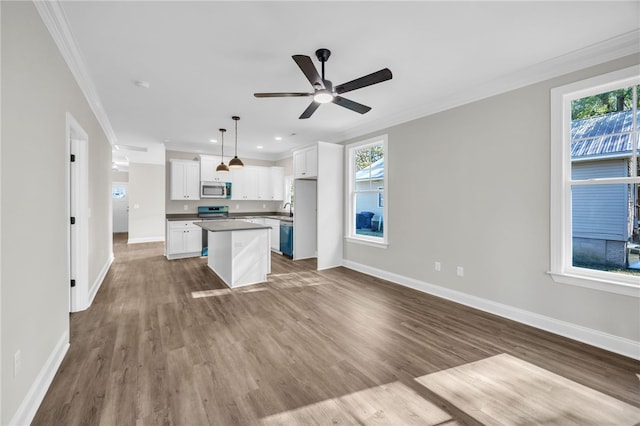 kitchen featuring appliances with stainless steel finishes, a center island, dark hardwood / wood-style floors, white cabinetry, and hanging light fixtures