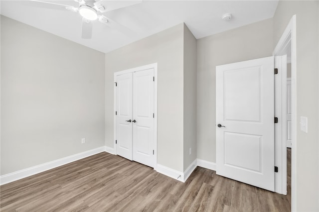 unfurnished bedroom with a closet, light hardwood / wood-style floors, and ceiling fan