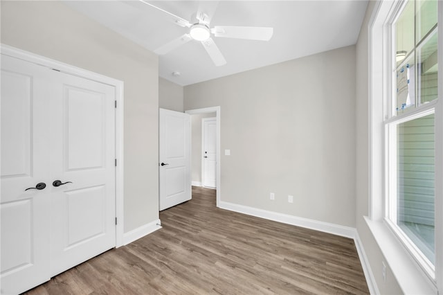 unfurnished bedroom with ceiling fan, a closet, and hardwood / wood-style flooring