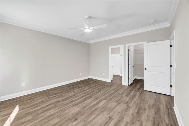 unfurnished bedroom with ceiling fan, crown molding, wood-type flooring, a spacious closet, and a closet