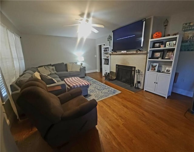 living room featuring a tile fireplace, ceiling fan, and wood-type flooring