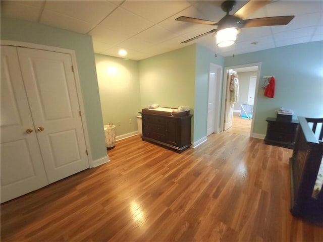 interior space with a paneled ceiling, ceiling fan, light wood-type flooring, and a closet