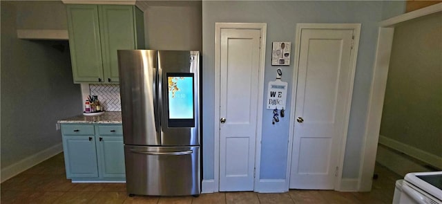 kitchen with stainless steel fridge, light stone countertops, backsplash, and light tile patterned floors