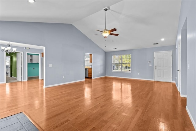 unfurnished living room featuring ceiling fan with notable chandelier, high vaulted ceiling, and light hardwood / wood-style flooring