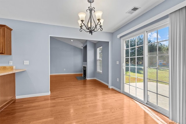 unfurnished dining area featuring light wood-type flooring and a chandelier