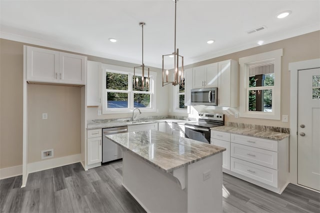 kitchen featuring white cabinets, appliances with stainless steel finishes, a kitchen island, and plenty of natural light