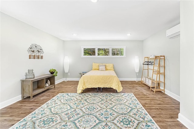 bedroom with hardwood / wood-style flooring and an AC wall unit