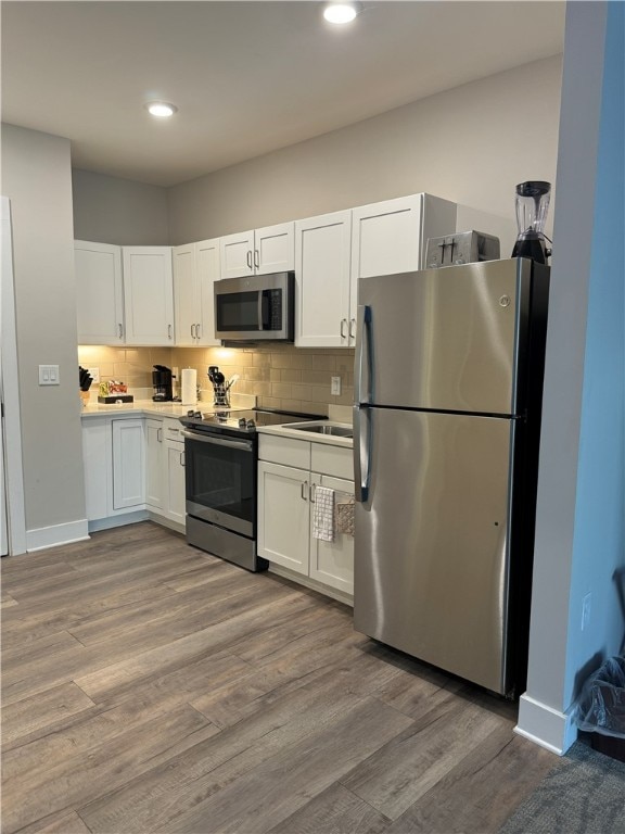 kitchen featuring stainless steel appliances, white cabinetry, tasteful backsplash, and light hardwood / wood-style flooring