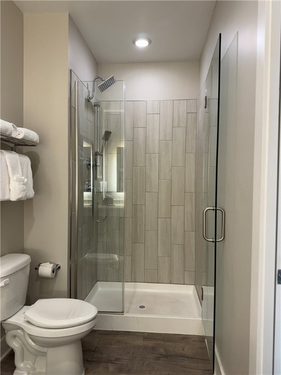 bathroom featuring hardwood / wood-style flooring, toilet, and a shower with door