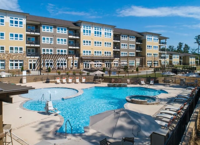 view of pool with a patio, pool water feature, and a hot tub