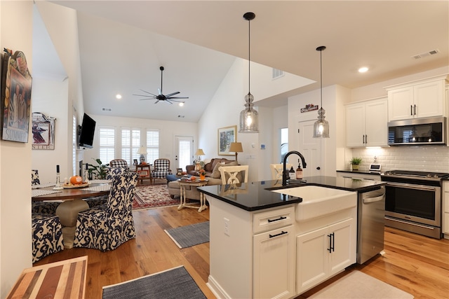 kitchen with a center island with sink, sink, light hardwood / wood-style flooring, white cabinetry, and stainless steel appliances