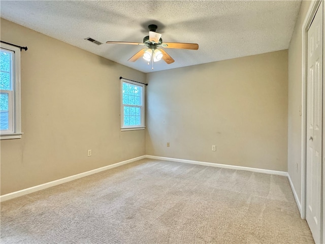 unfurnished bedroom featuring ceiling fan, light colored carpet, and a textured ceiling