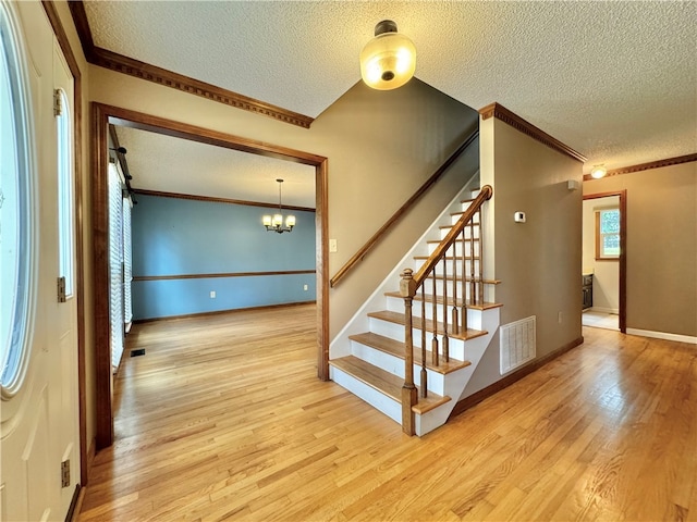 stairway with a chandelier, a textured ceiling, and hardwood / wood-style flooring