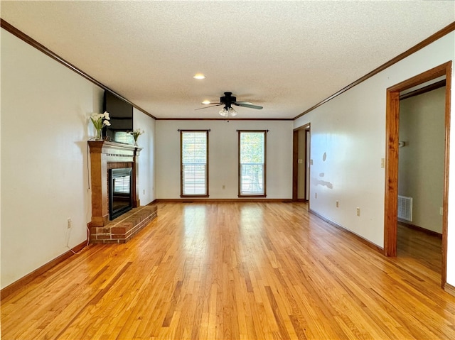 unfurnished living room featuring ceiling fan, crown molding, light hardwood / wood-style floors, a textured ceiling, and a fireplace