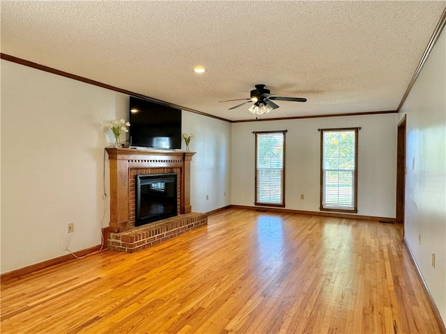 unfurnished living room featuring a brick fireplace, ornamental molding, a textured ceiling, ceiling fan, and light hardwood / wood-style floors