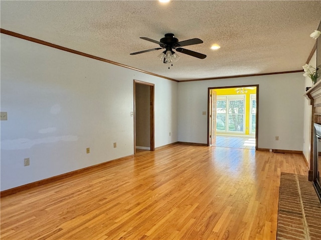 unfurnished living room with a textured ceiling, ceiling fan, crown molding, light hardwood / wood-style flooring, and a fireplace