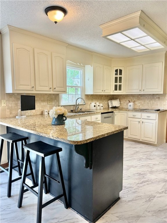 kitchen with white cabinetry, sink, a kitchen breakfast bar, light stone counters, and kitchen peninsula