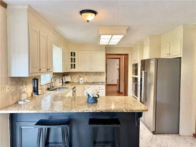 kitchen featuring light stone countertops, kitchen peninsula, sink, and appliances with stainless steel finishes