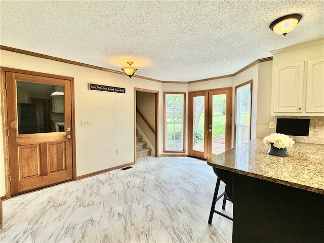 kitchen featuring white cabinetry, crown molding, light stone countertops, and a textured ceiling