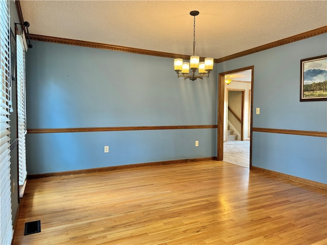 unfurnished room featuring ornamental molding, a chandelier, a textured ceiling, and light wood-type flooring