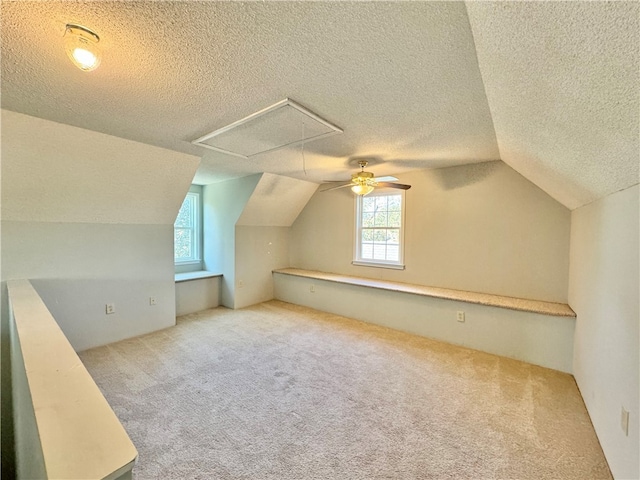 additional living space featuring ceiling fan, light colored carpet, lofted ceiling, and a textured ceiling