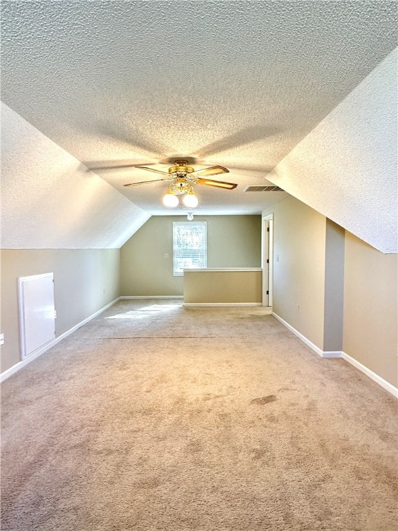 additional living space with vaulted ceiling, carpet, and a textured ceiling