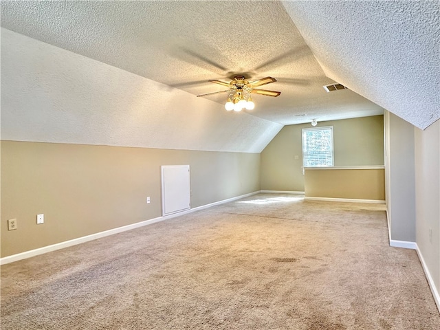 additional living space featuring ceiling fan, a textured ceiling, light carpet, and vaulted ceiling